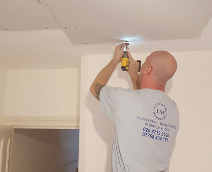 A plasterer plasterboarding a ceiling in Croydon